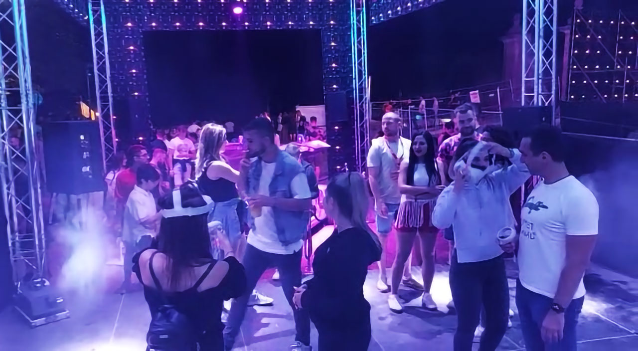A dynamic scene at the EXIT Festival's VR Zone with festival-goers engaging in a lively party atmosphere. People are dancing and interacting with each other under purple-tinted lights, surrounded by stage equipment. This encapsulates the immersive experience created by Digital Mind, allowing participants to virtually step into the vibrant environment of the EXIT Festival as if they were present during the event itself.