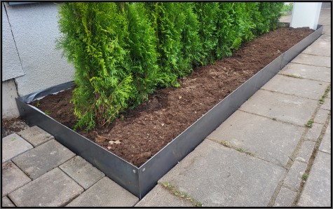 Rabattkanter i orostad Corten som skiljer av mellan rabatt och trottoar.