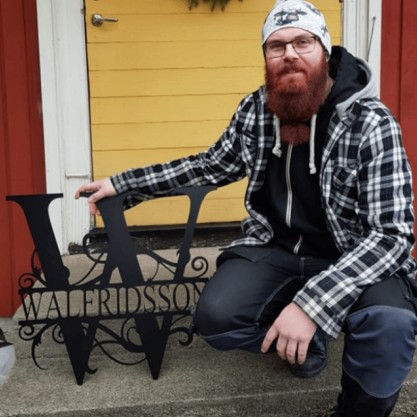 Man med stort metallmonogram på stentrappa.