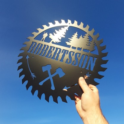 Svart metallskylt skuren som en sågklinga hållls upp mot blå himmel.