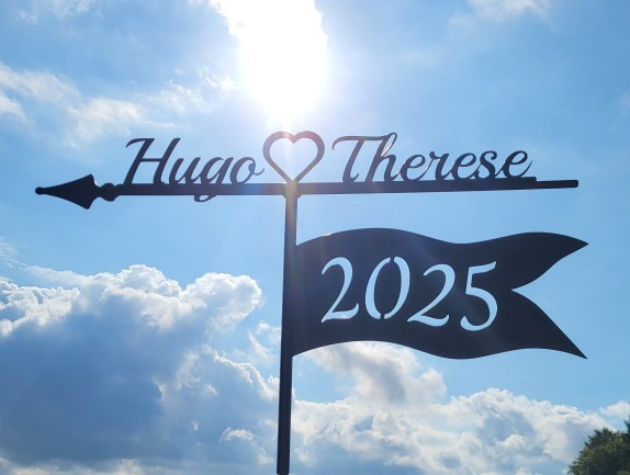 Personlig vindflöjel med årtal utskuret ur vimpeln och två namn samt ett hjärta som förmedlar vilka som bor där flöjel finns monterad.