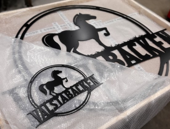 Stor skylt bestående av en utskuren logga med hästmotiv.