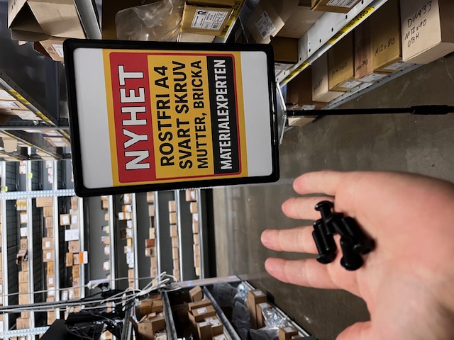 Skylt i butiken hos Materialexperten som visar nyheten svarta rostfria A4-skruvar, muttrar och brickor