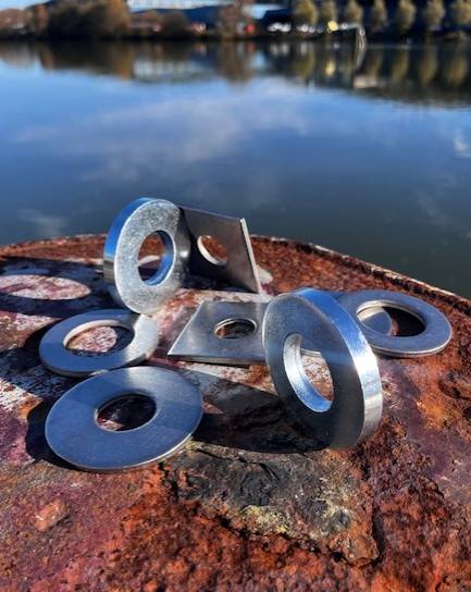 Brickor i rostfritt A4, varmförzinkat och tjockt utförande fotograferade utomhus vid vattnet – plan-, fyrkants- och distansbrickor från Materialexperten