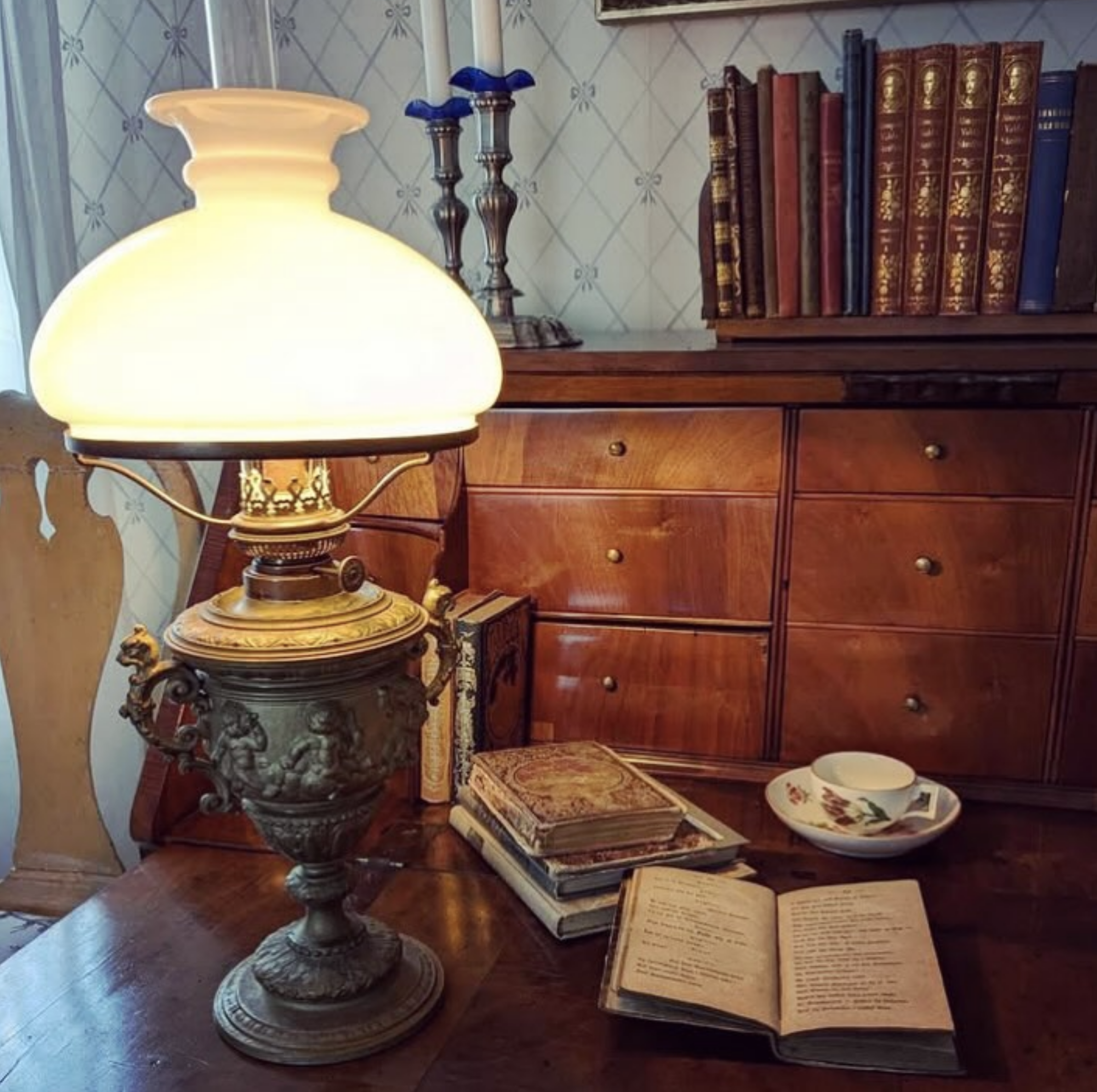 En vacker antik bordslampa med en kosmosbrännare och en vestaskärm