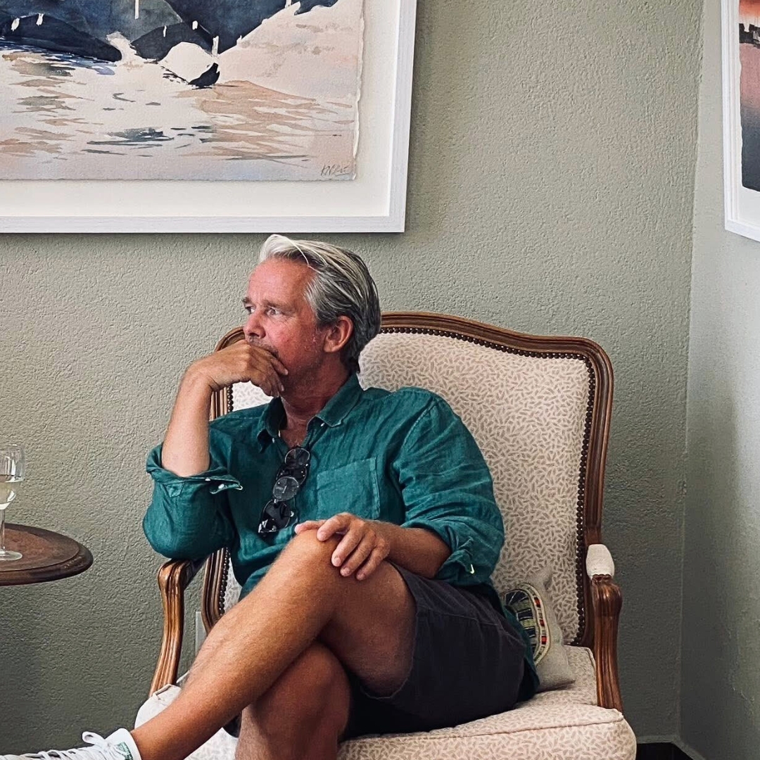 Kalle Nilsson i fåtölj omgiven av akvareller