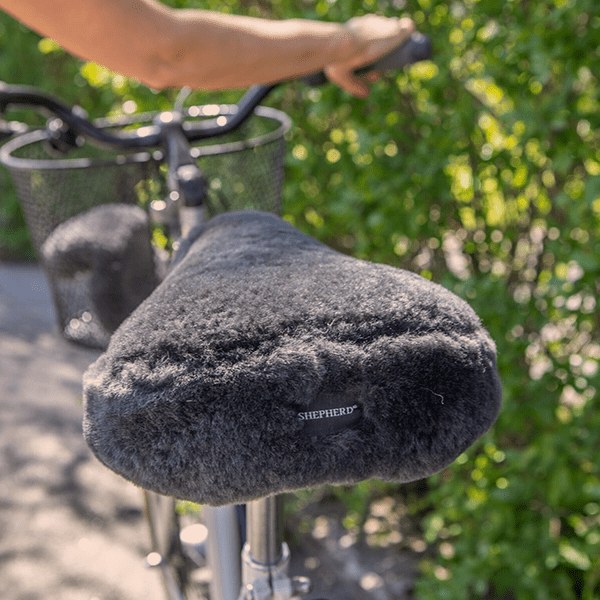 Mörkgrått sadelskydd i fårskinn monterat på en cykel utomhus