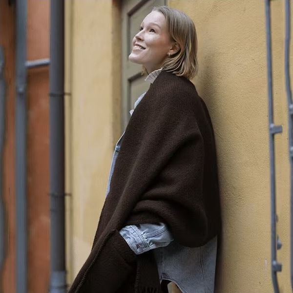 Kvinna med mörk ullsjal med fickor i stadsmiljö