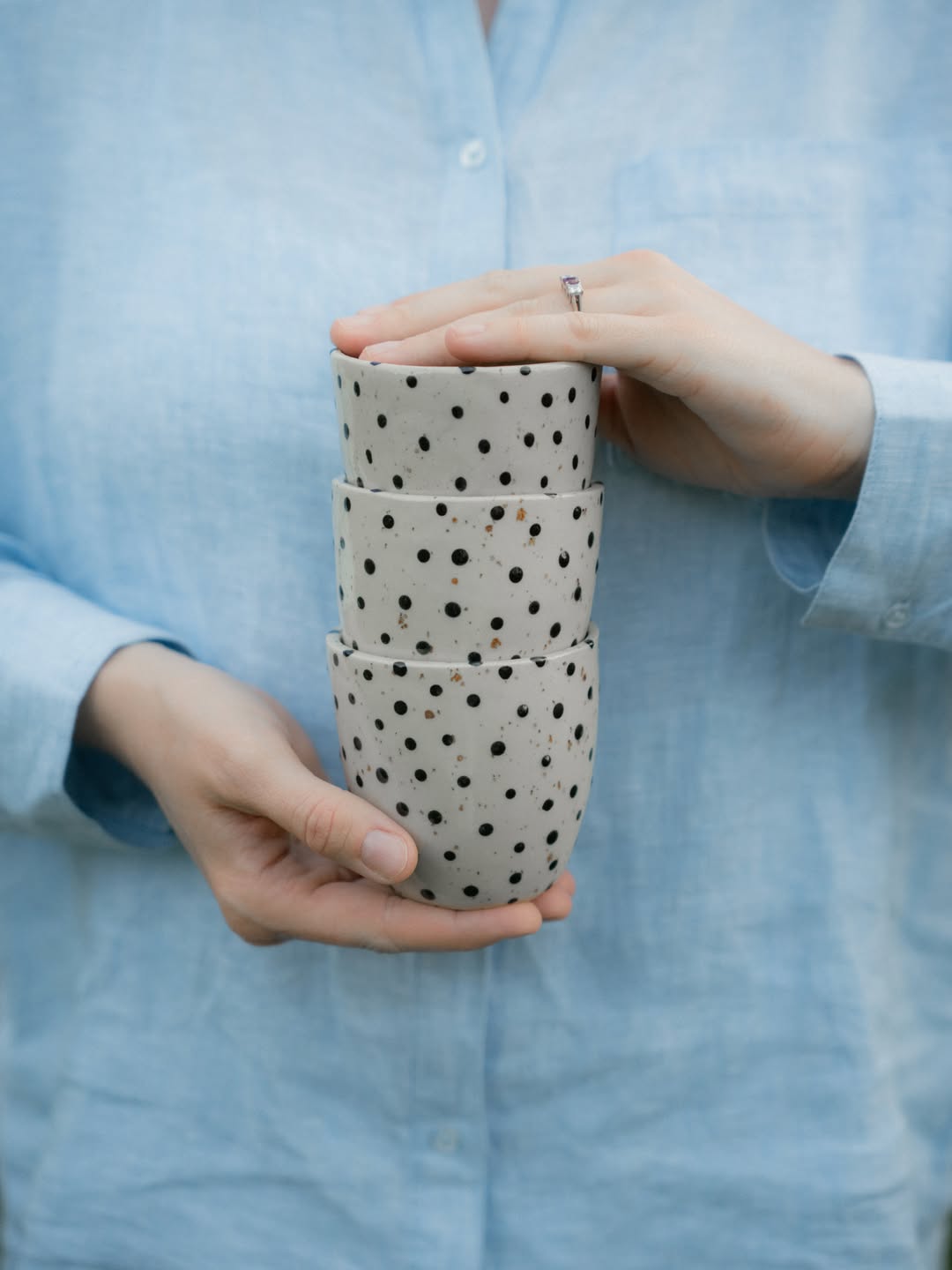 Handgjorda muggar med prickar, staplade i en hand