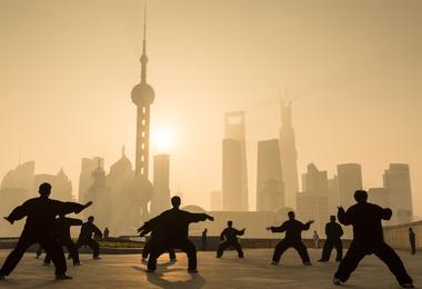 A group practices tai chi in front of Shanghai's skyline