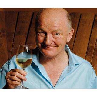 Oz Clarke holding up a glass of white wine