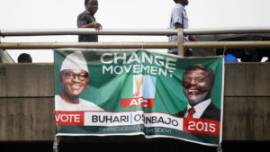 Men walk past a banner hanging from a bridge campaigning for All Progressives Congress (APC) Presidential candidate Buhari and his running-mate Osinbajo, in Lagos