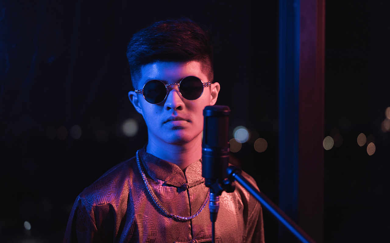 Artist portrait of Luther Wong wearing sunglasses in front of a microphone