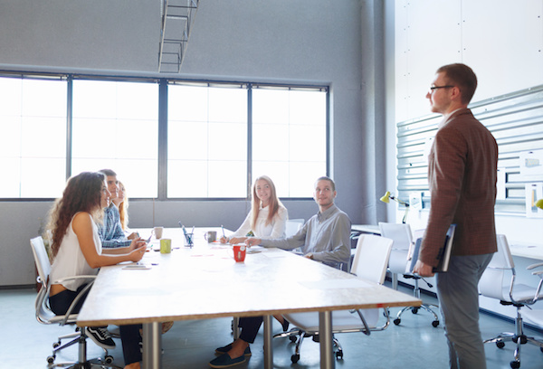 A photo of people sitting around a table in an office.