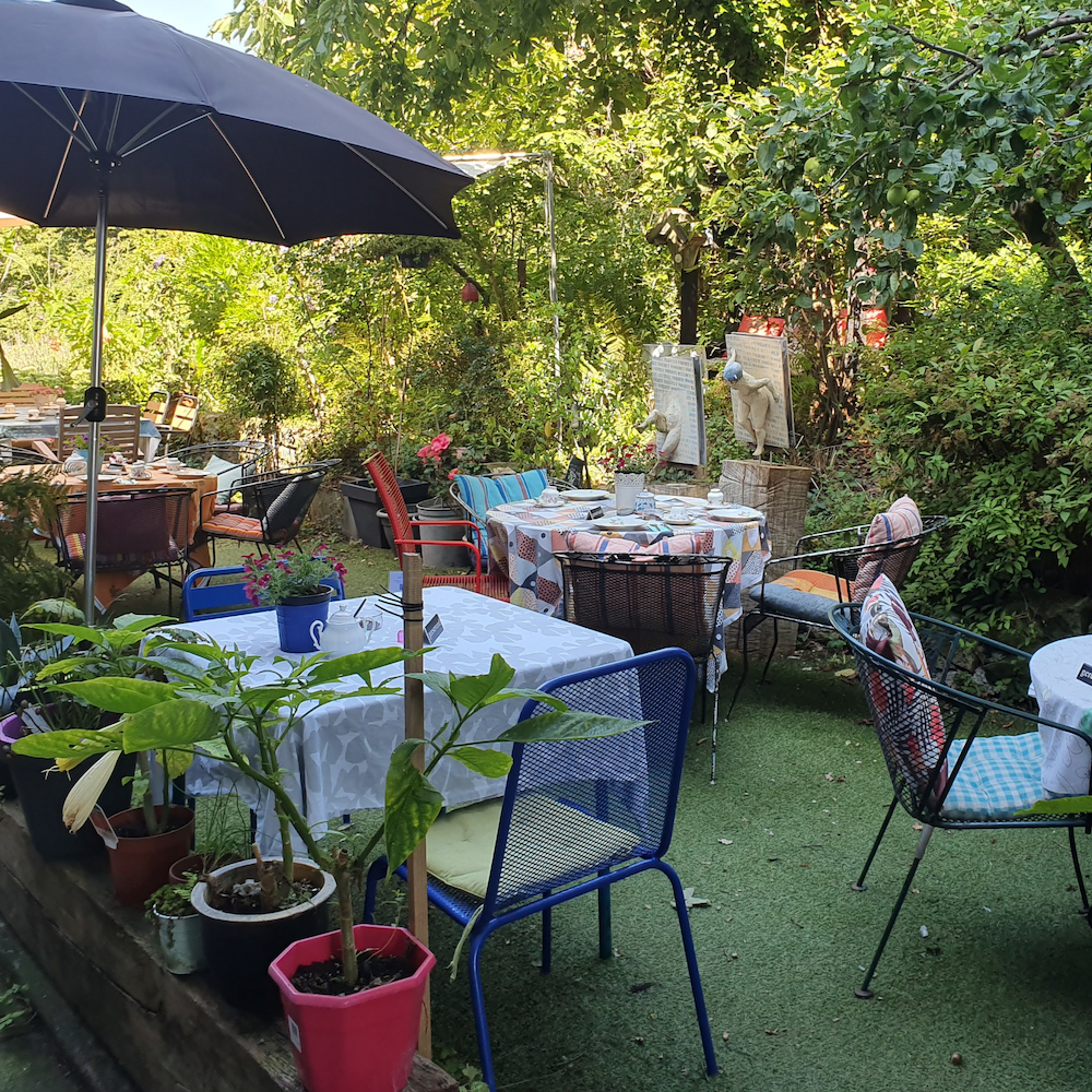 Gedekte tafeltjes in de tuin bij een theehuis
