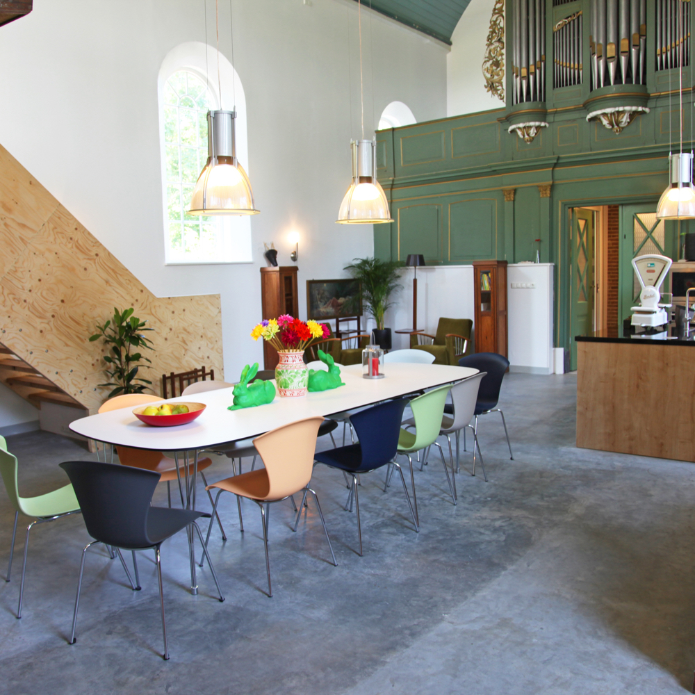 Een lange tafel met kleurrijke stoelen in de eethoek