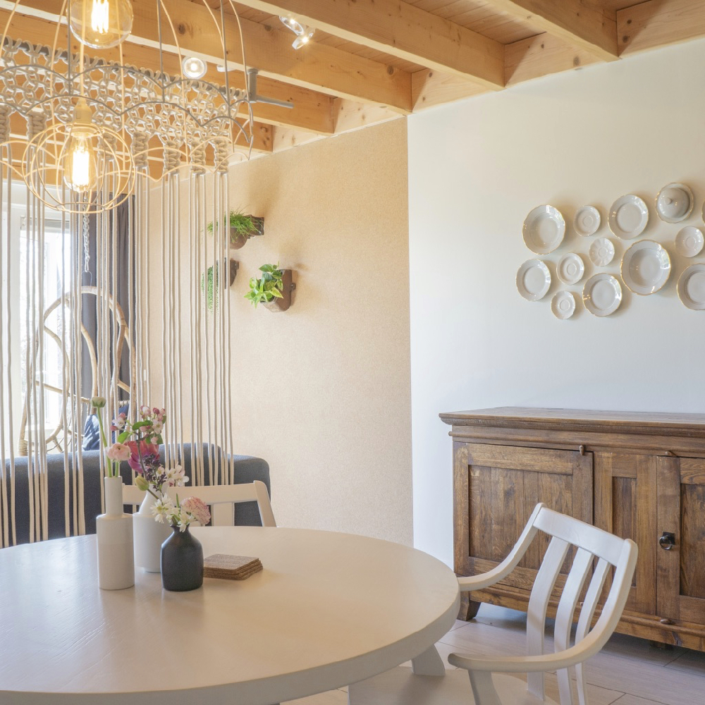 Appartement met bordjes aan de muur, een ronde zithoek en stoere houten balken