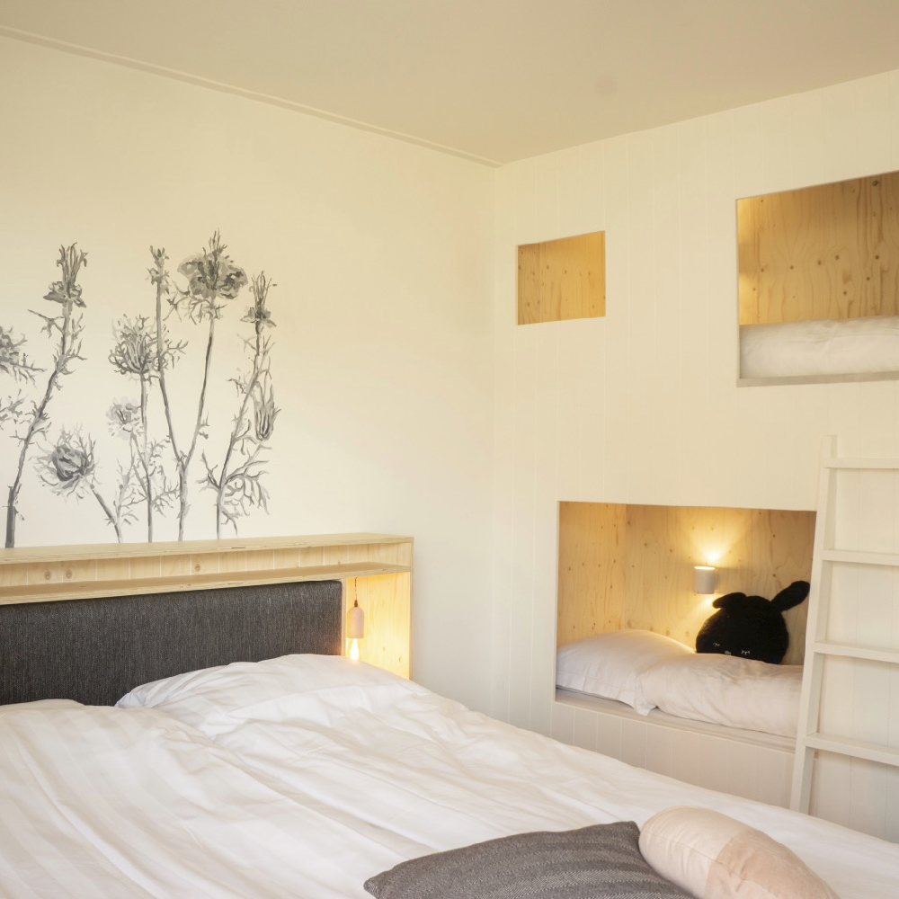 Tweepersoons bed met ernaast een hip stapelbed in de muur