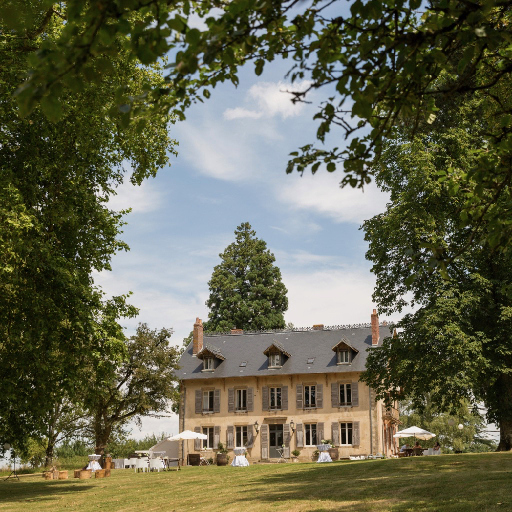 Domaine de Savigny tussen de bomen, met witte stoelen voor het huis