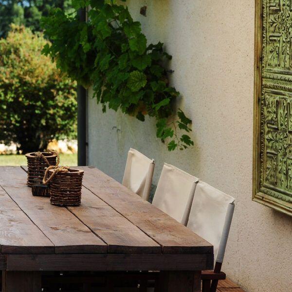 Close up van de eettafel op het terras met een kant drie regisseurstoelen
