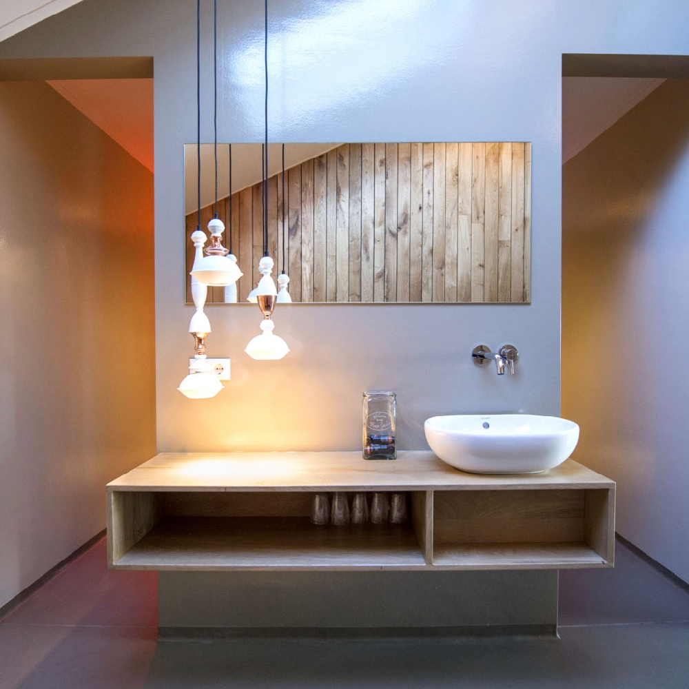 Wastafel op houten design wasmeubel met tros witte hanglampen