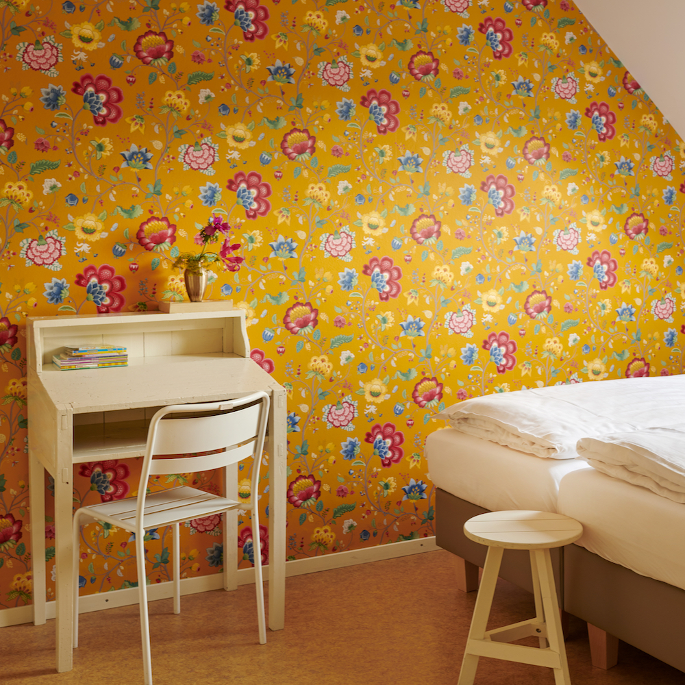Slaapkamer in vakantiehuis met hip behang, okergeel met bloemen