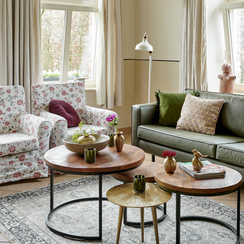 Landelijk ingerichte woonkamer met donkergroene bank en gebloemde fauteuils