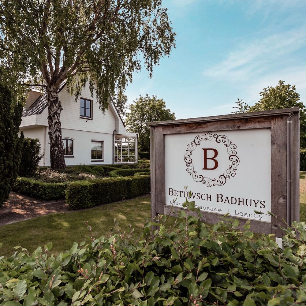 Wit huis met groene hagen, met daarin een privé sauna