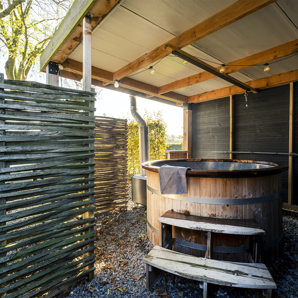 Houten hot tub onder een overkapping