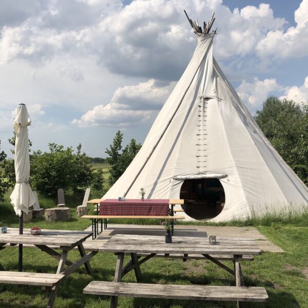 Grote tipi met picknicktafels ervoor