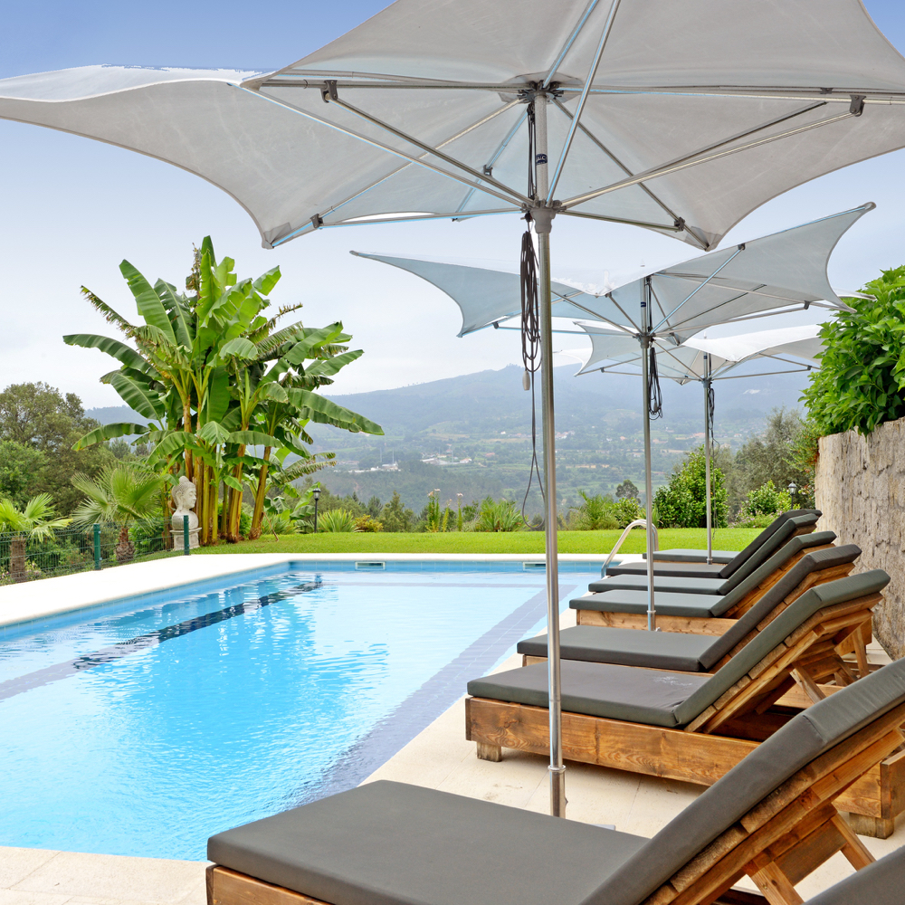Zwembad met ligstoelen en witte parasols