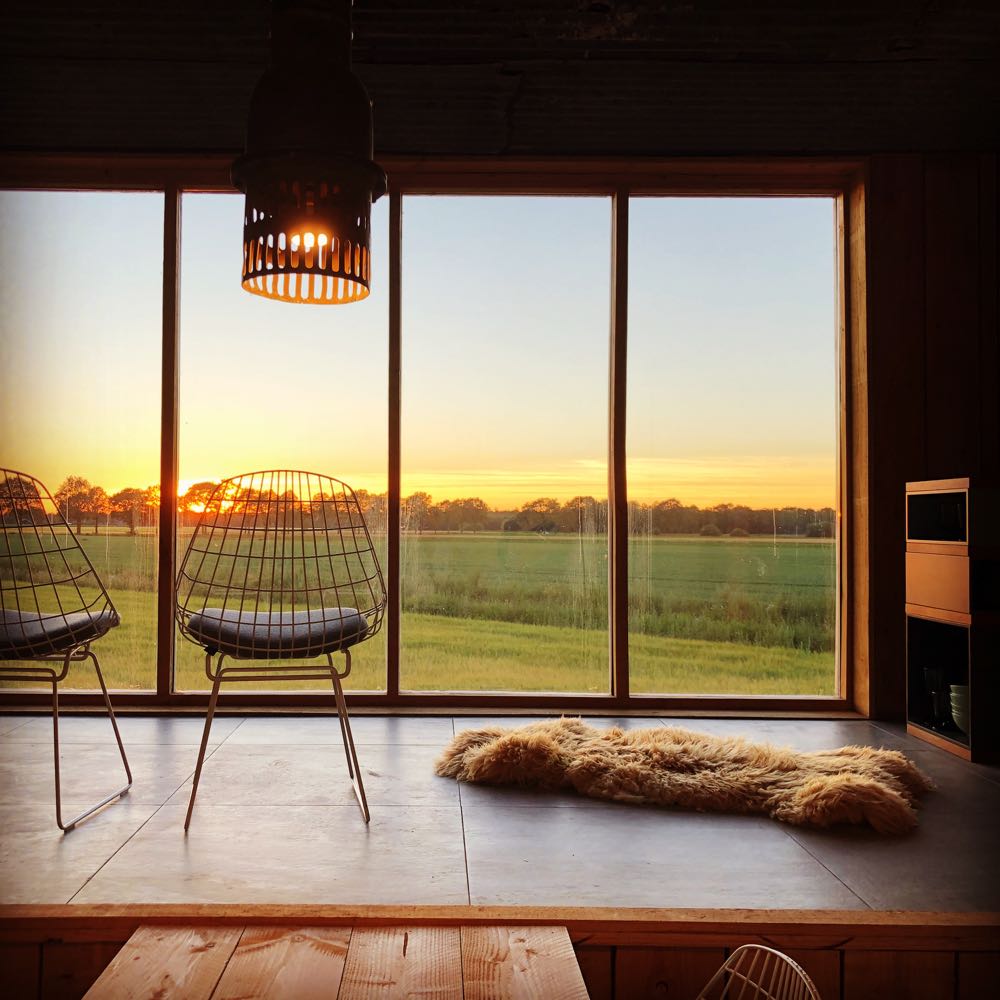 Duurzaam vakantiehuis met grote ramen en twee stoelen voor het raam