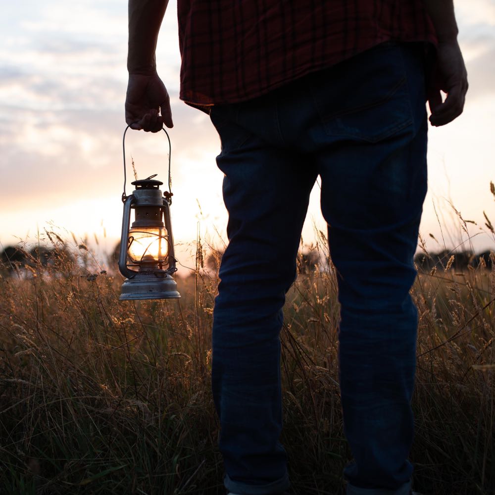 Man met olielamp voor de zonsondergang