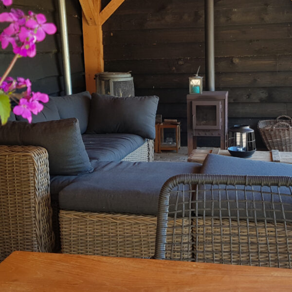 Veranda met houtkachel en loungebanken bij het vakantiehuis