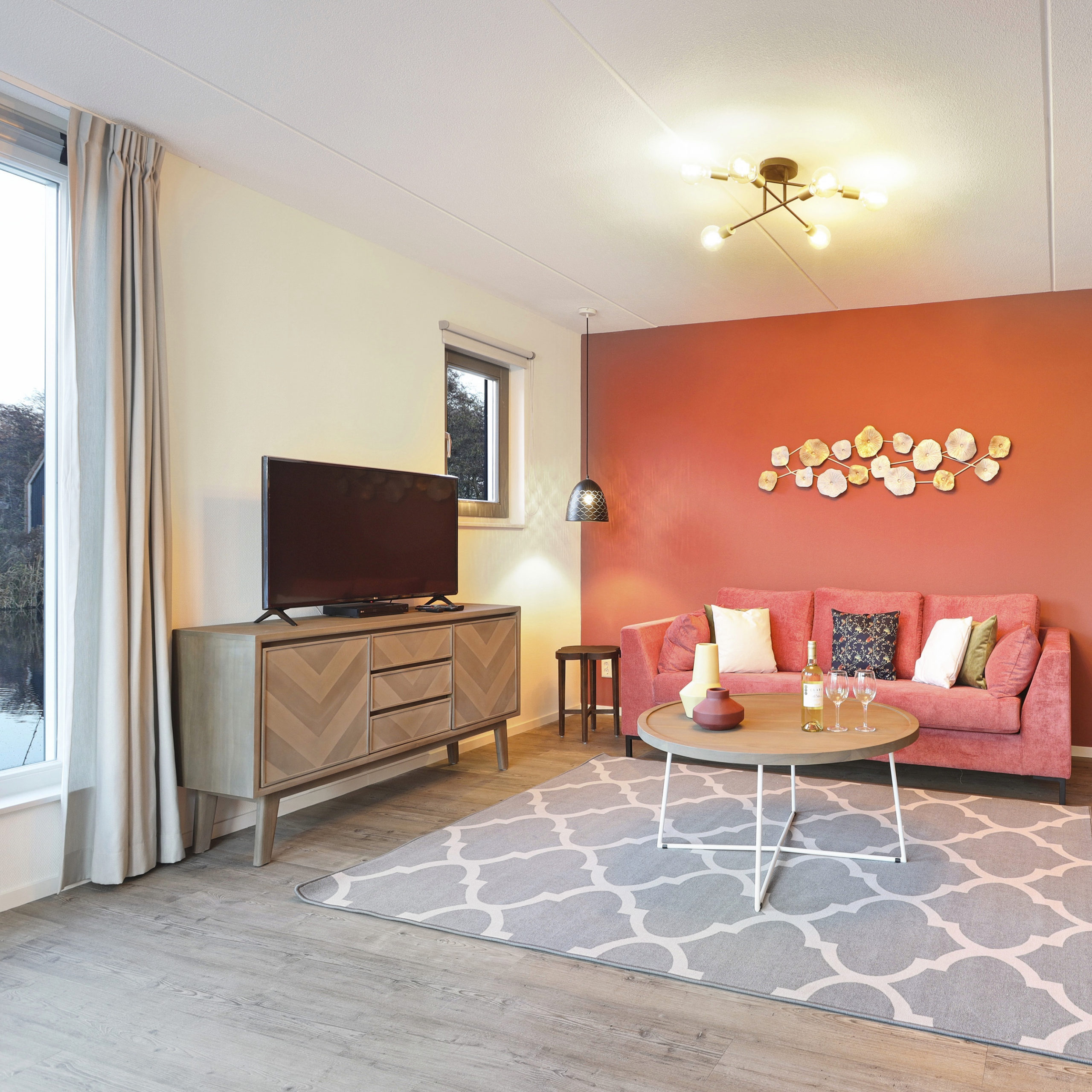 Woonkamer met lekker vloerkleed, roze bank en roze muur in vakantiehuis van Landal