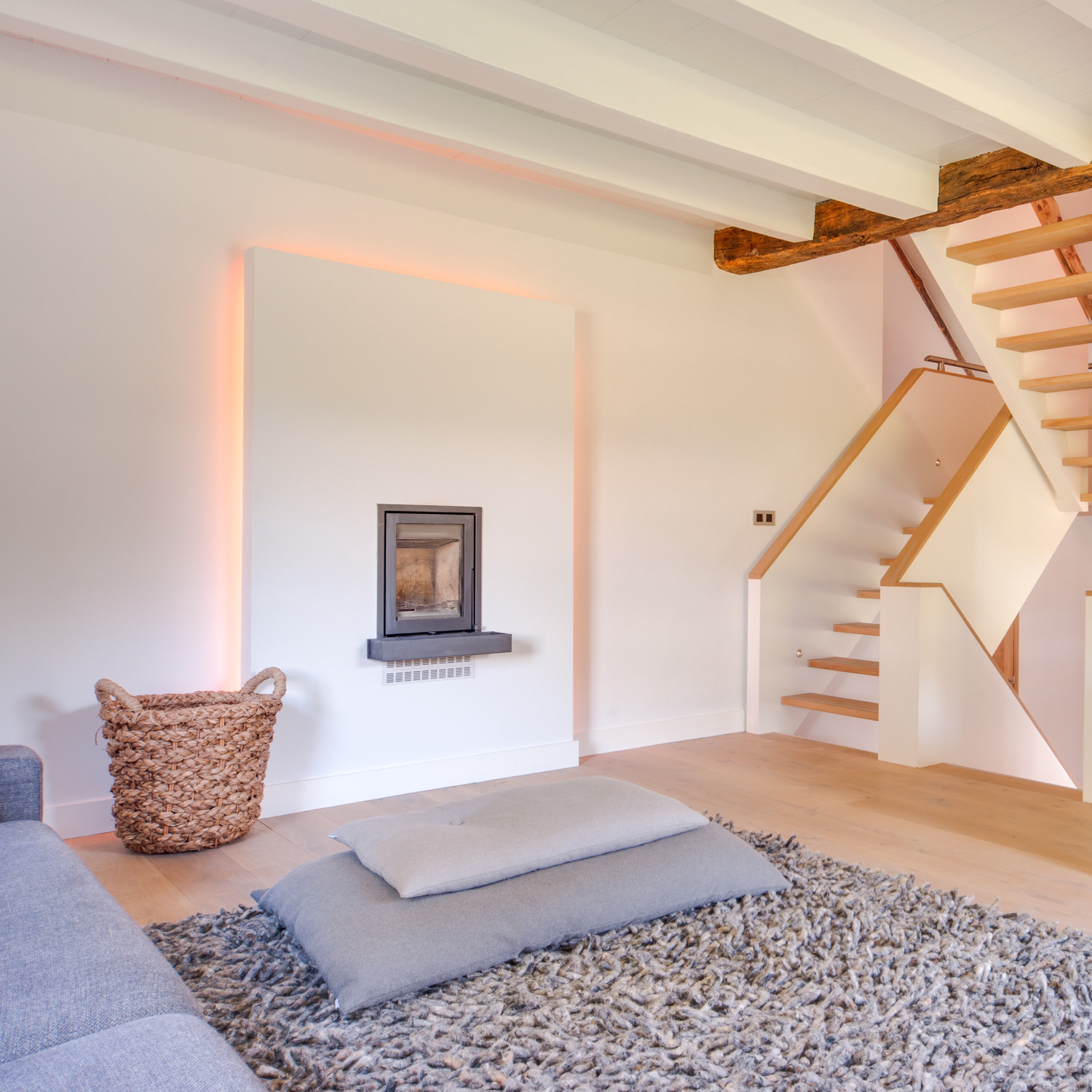 Tapijt met kussens op de grond en een houtkachel