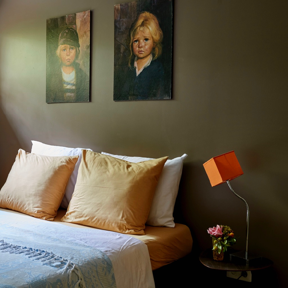 Slaapkamer met tweepersoons bed, 2 schilderijen aan de muur, oranje lampen op het nachtkastje