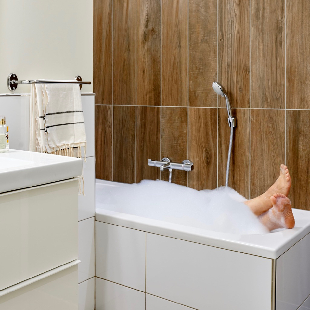Badkamer met ligbad met een laag schuim en voeten die er uit steken