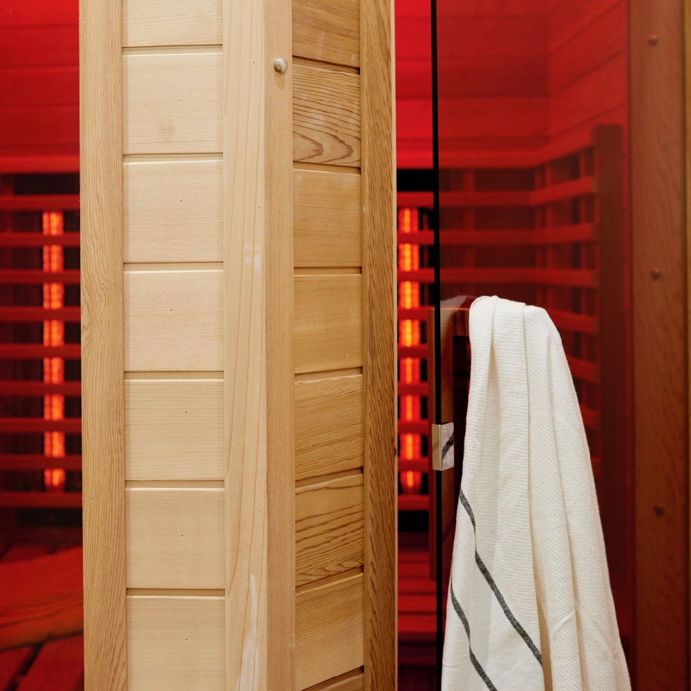 Sauna met rode lampen en een badjas aan de deur