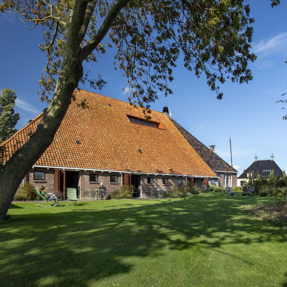 Zijkant van een boerderij in Friesland, met groen grasveld ervoor