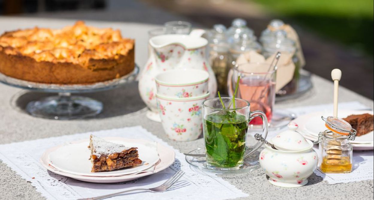 Mooi sfeerbeeld van tafel met taart en theeeservies en muntthee met potje honing