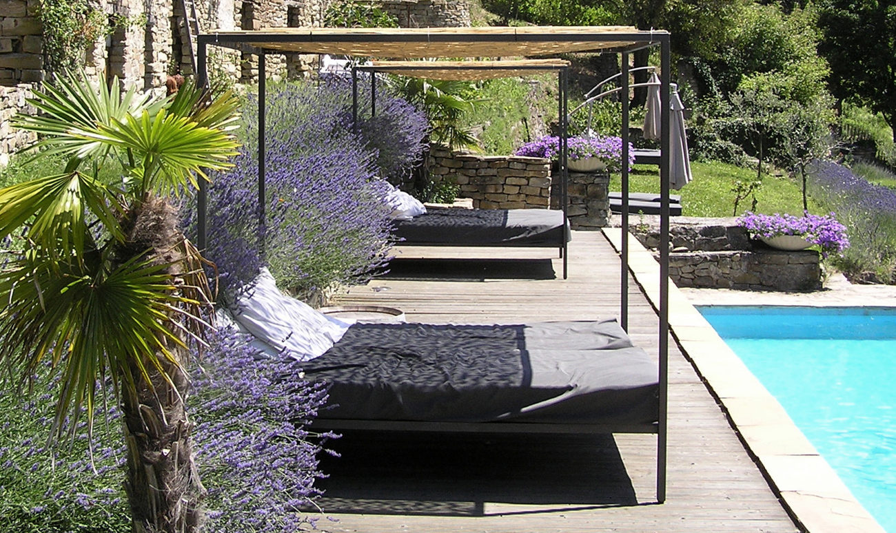 Loungebedden naast zwembad op houten deck met mooie planten en bloemen