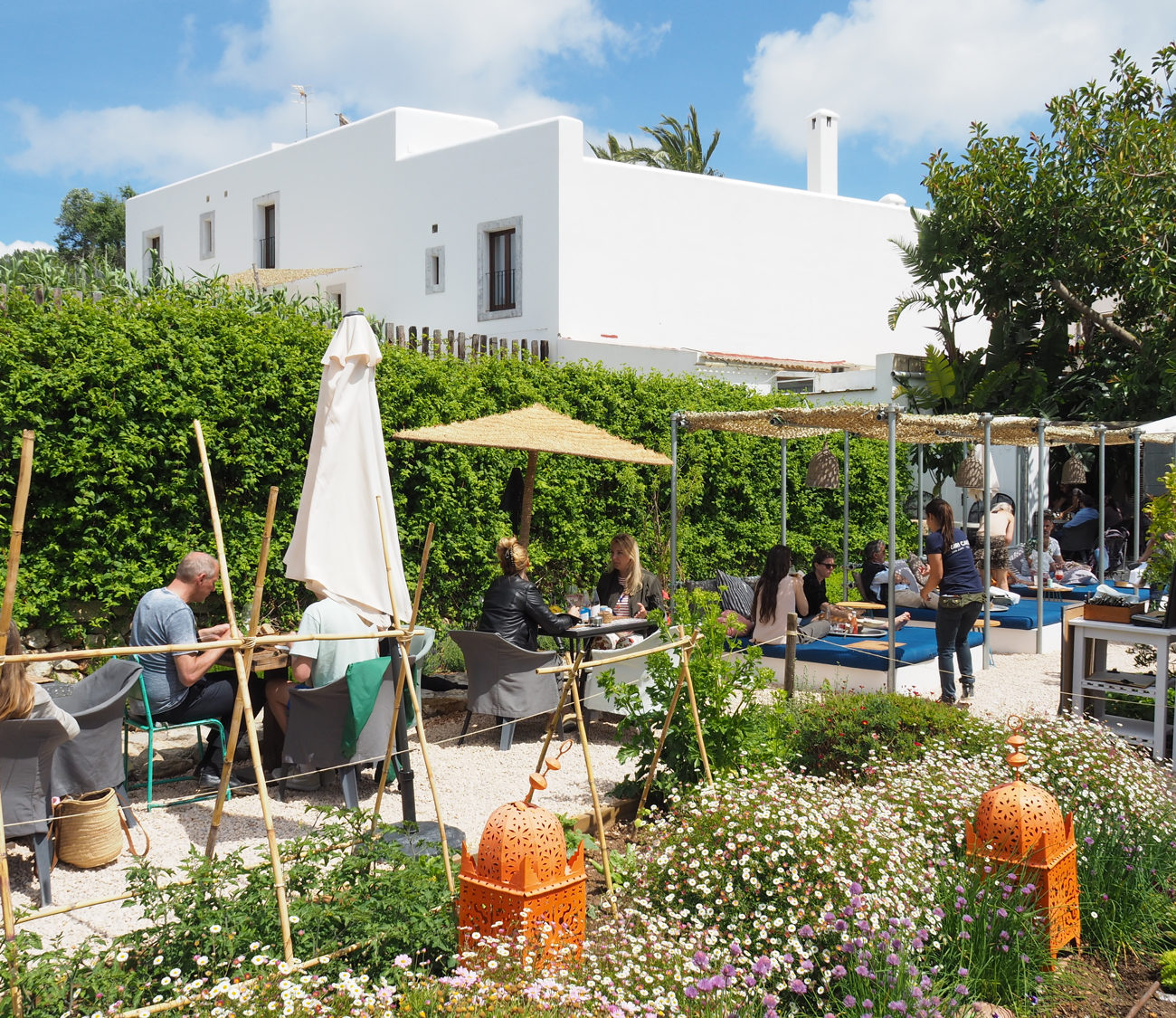 Terras met loungeplekken en tafels waar mensen aan het eten zijn in bloementuin