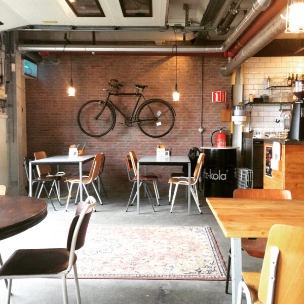 Koffie adres bij het Honigcomplex in Nijmegen. Stoer interieur met perzisch tapijt en fiets aan de wand.