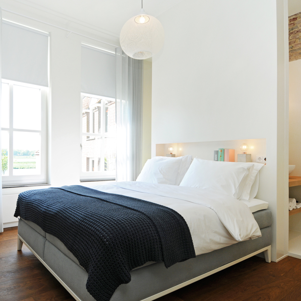 Luxe B&B kamer met groot tweepersoons bed voor hoge ramen, wit beddengoed en zwarte sprei