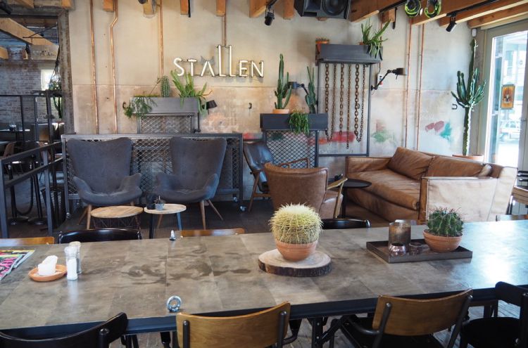 Tafel met stoelen, een cactus erop en aan de wand het woord stallen