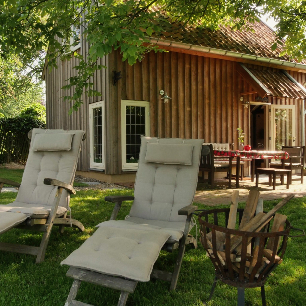 Ligstoelen voor een terrasje voor een huis in een groene omgeving