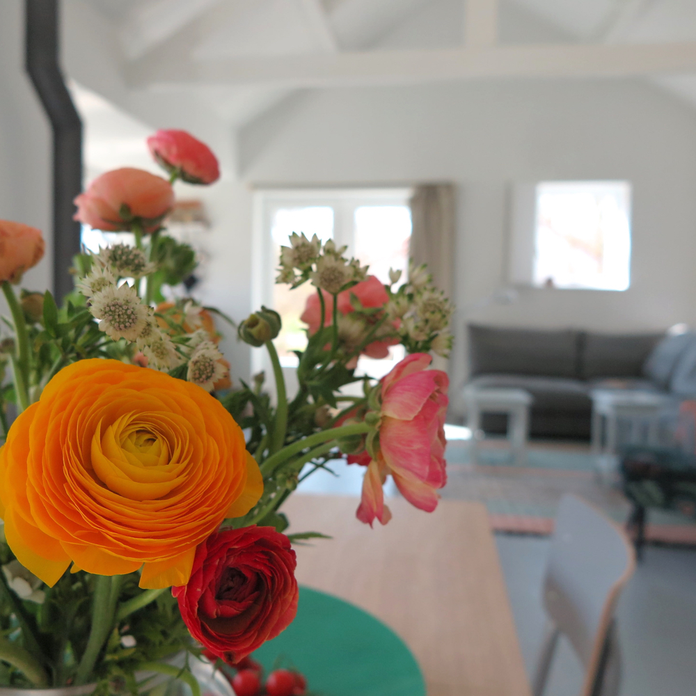 Bloemen op de eettafel en doorkijkje naar de zithoek