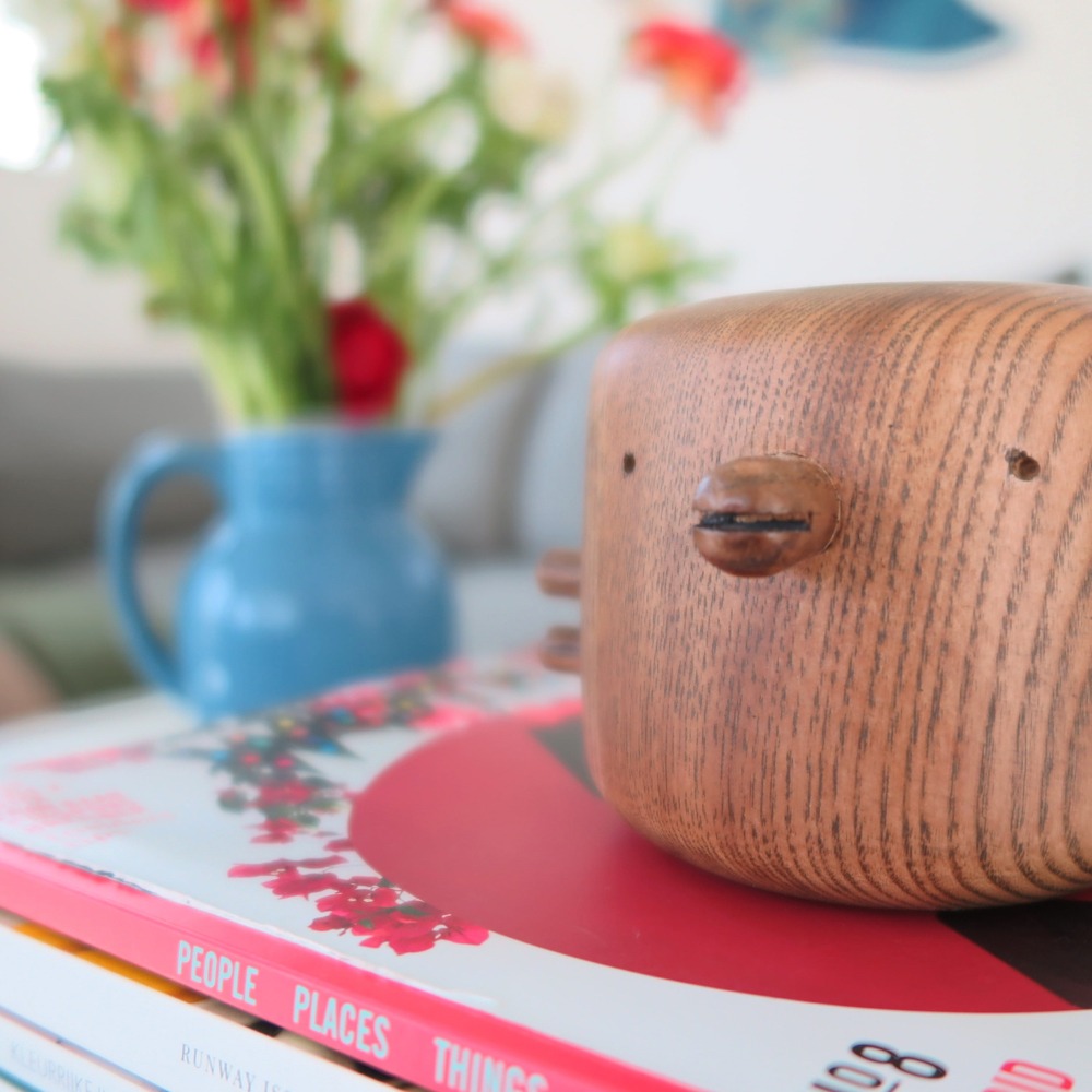Een houten vogel op een stapel boeken met bloemen