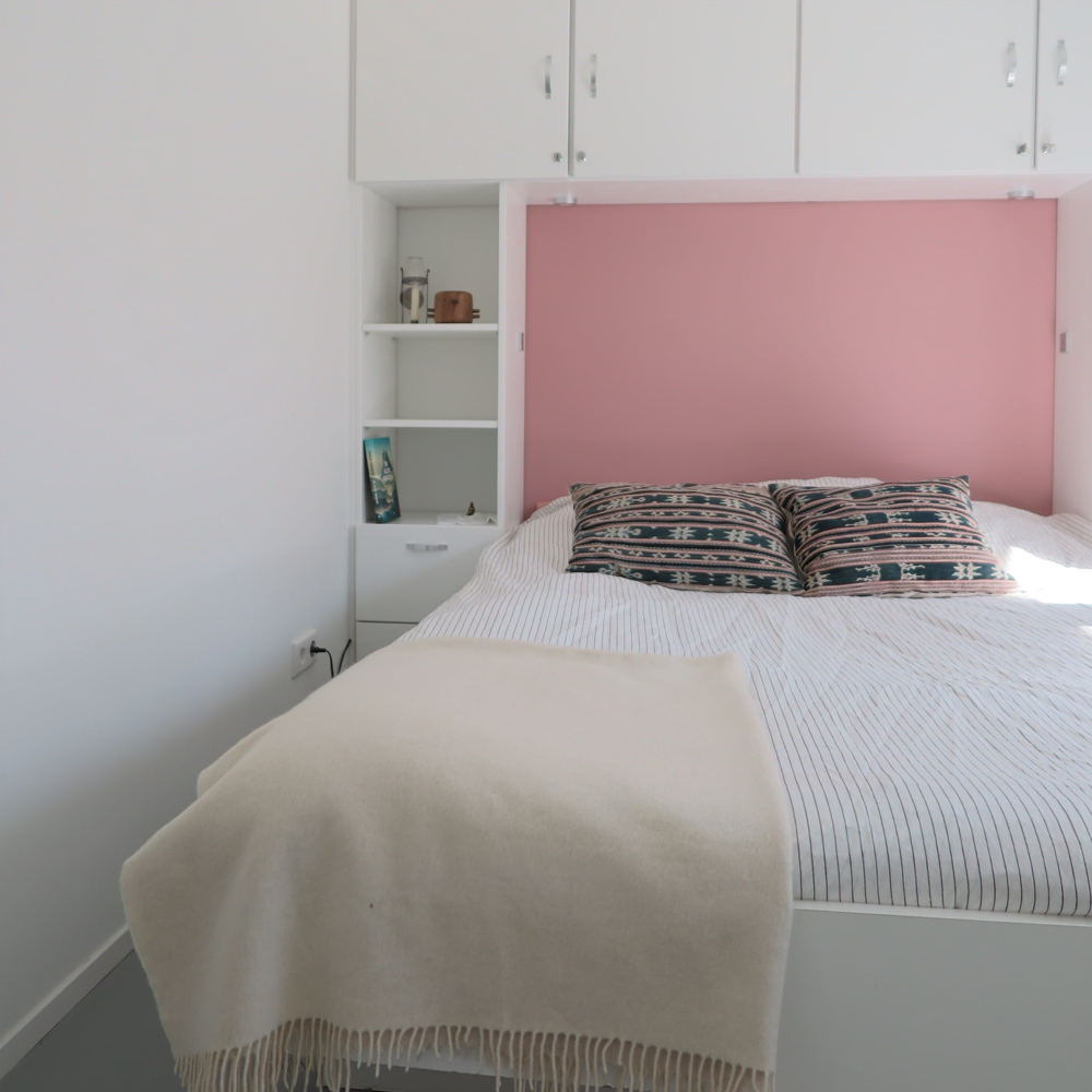 Tweepersoons bed met roze achterwand met kasten